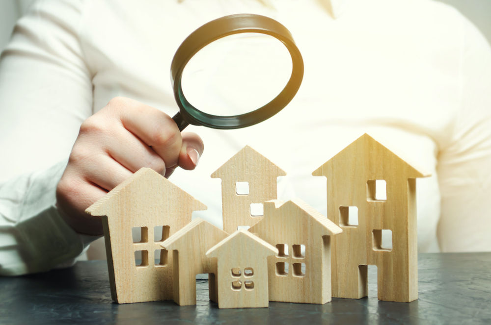 A woman is holding a magnifying glass over a wooden house