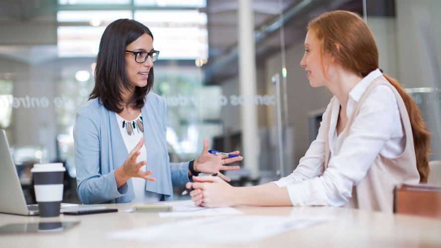 Two women discussing ISA transfer details in office meeting