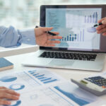 Professional financial advisor reviewing investment portfolio charts and graphs on a computer screen