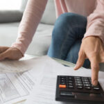 Person managing personal finances with calculator and documents