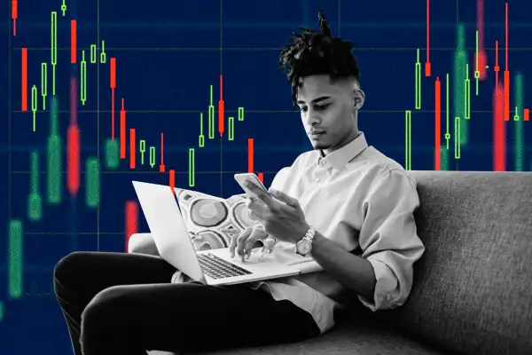 Young professional using smartphone and laptop with financial charts