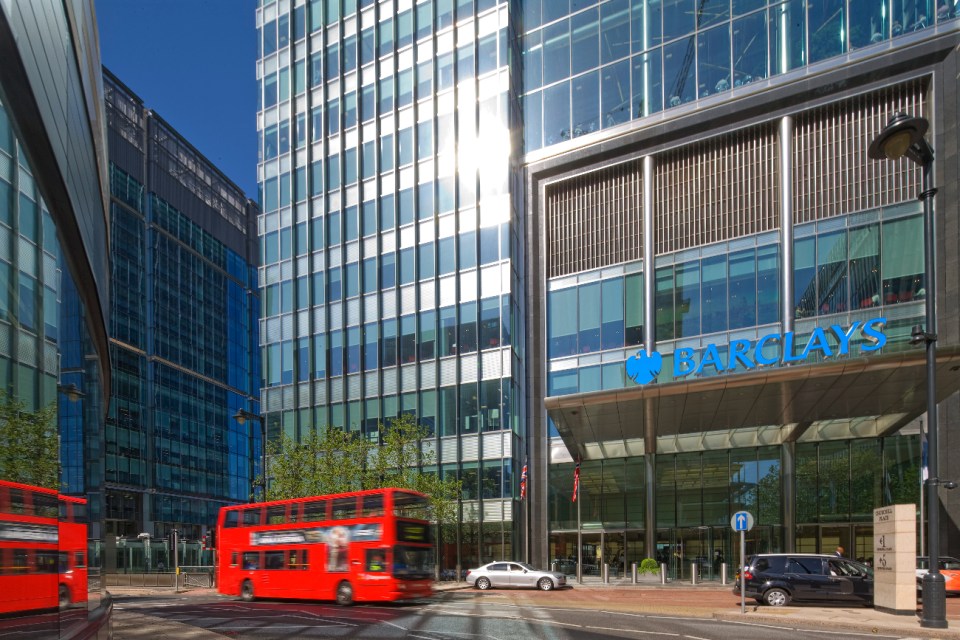 Barclays headquarters entrance at Churchill Place in Canary Wharf with London buses passing by