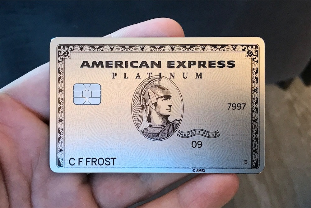 Hand holding a metal American Express Platinum Card, showcasing the premium physical design and weight that reflects the company's focus on affluent customers