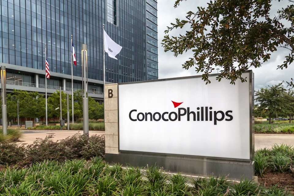 ConocoPhillips corporate signage at company headquarters with American and Texas flags in the background