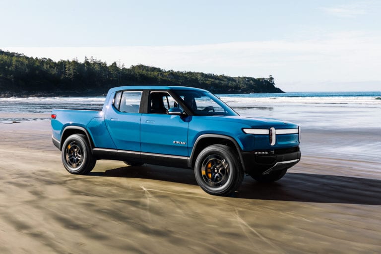 Rivian R1T electric pickup truck on beach showcasing all-terrain capabilities
