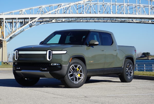 Rivian R1T in Launch Green color positioned near waterfront bridge location