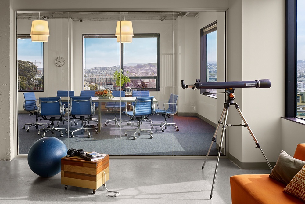 Modern Asana office interior featuring a glass-walled conference room with blue chairs and city views