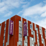Premier Inn logo displayed on the exterior of a building, photographed from below against the sky.