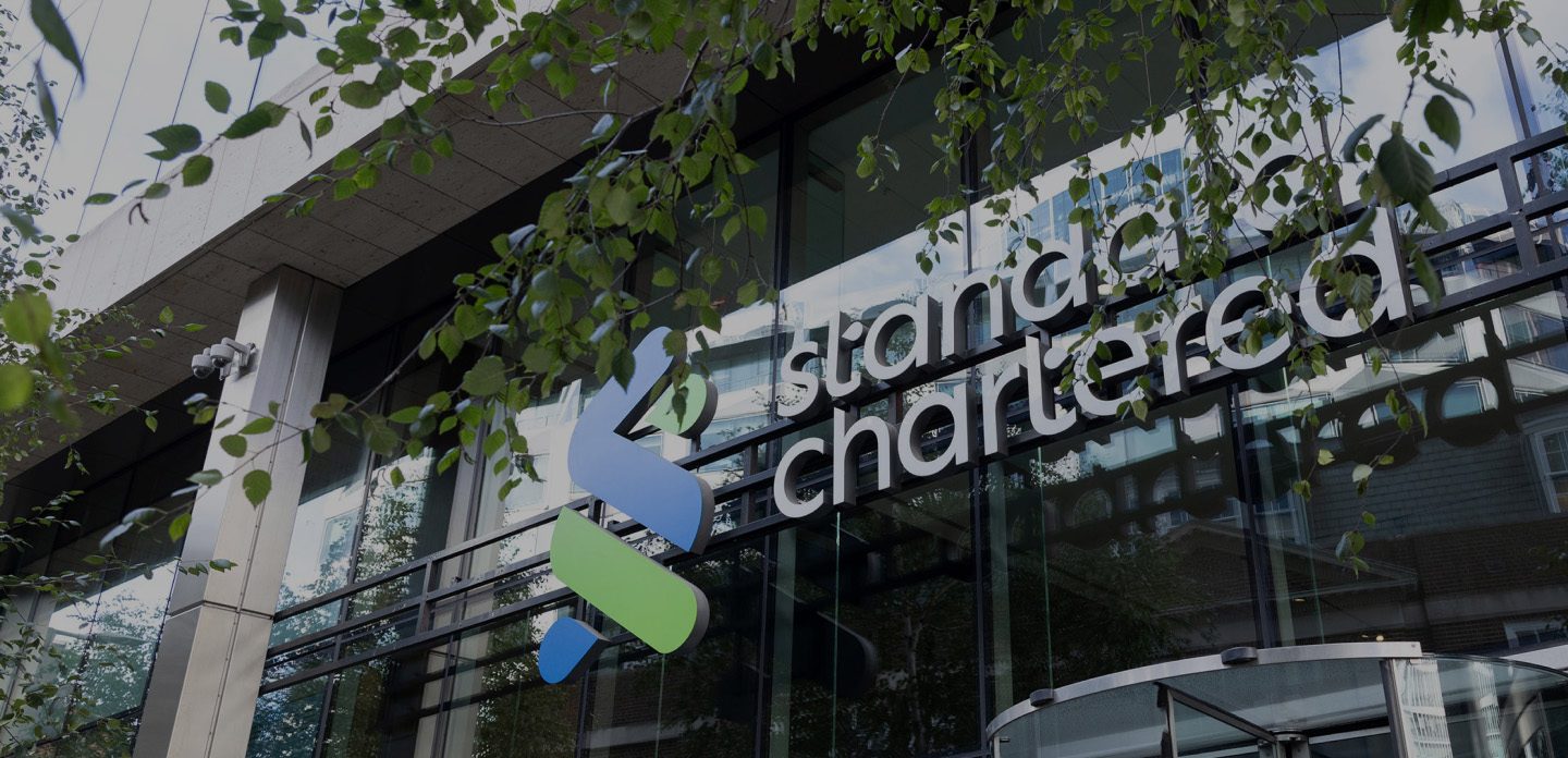 Front exterior of Standard Chartered's London office building with company signage above the entrance.