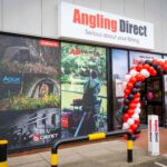 Exterior of an Angling Direct fishing tackle store with signage and a balloon arch at the entrance