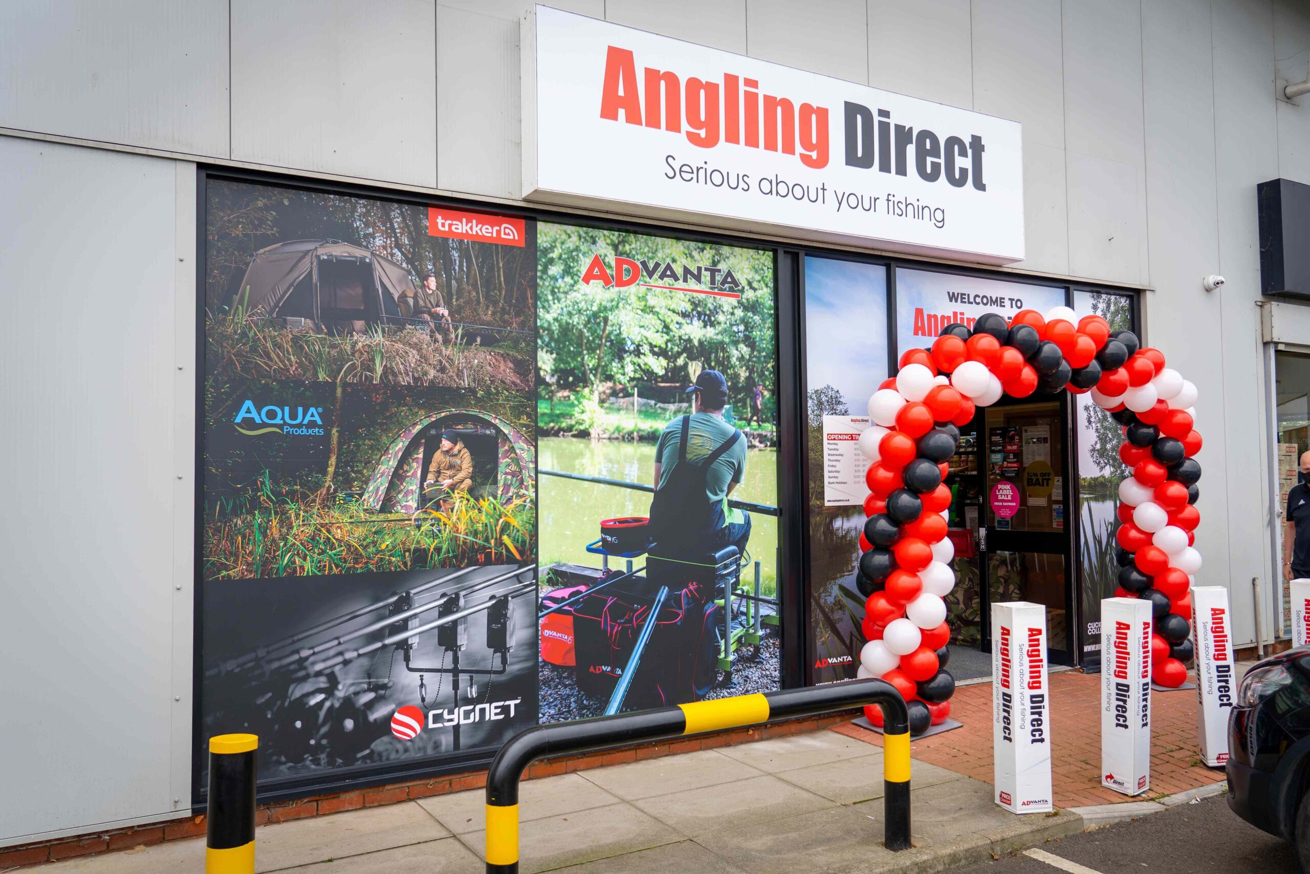 Exterior of an Angling Direct fishing tackle store with signage and a balloon arch at the entrance