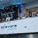 Bravura Solutions executives celebrate with confetti at a stock exchange Market Open ceremony, with the Bravura Solutions logo displayed on a banner.