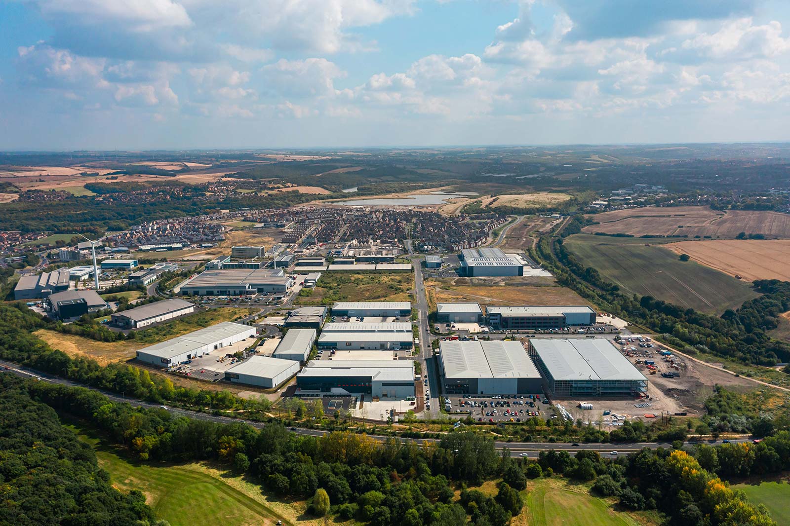 Aerial view of a large industrial and logistics estate with warehouses, surrounded by farmland and residential areas.