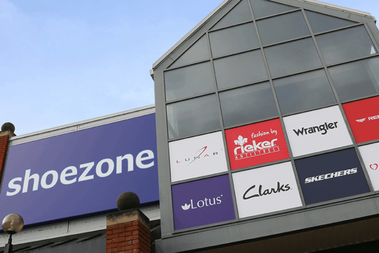 Exterior of a Shoe Zone store showing the shoezone sign and footwear brand logos on the shopfront.
