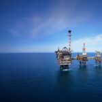 Aerial view of an offshore oil and gas platform in the North Sea under a clear blue sky