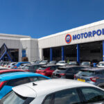 Exterior of a Motorpoint car dealership with a car park full of vehicles under a clear blue sky