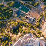 Aerial drone view of mine site water storage ponds and infrastructure surrounded by bushveld vegetation, consistent with Caledonia Mining's African gold mining operations.