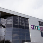 Exterior of Advanced Medical Solutions Group headquarters building with illuminated AMS logo and wordmark on the facade.