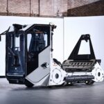 Aurrigo autonomous ground support vehicle with towing frame displayed in an industrial facility, branded with the Aurrigo name and logo.