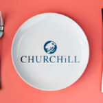 A white plate bearing the Churchill logo, flanked by a fork and knife, on a coral background.