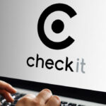 Hands typing on a laptop displaying the Checkit logo on screen