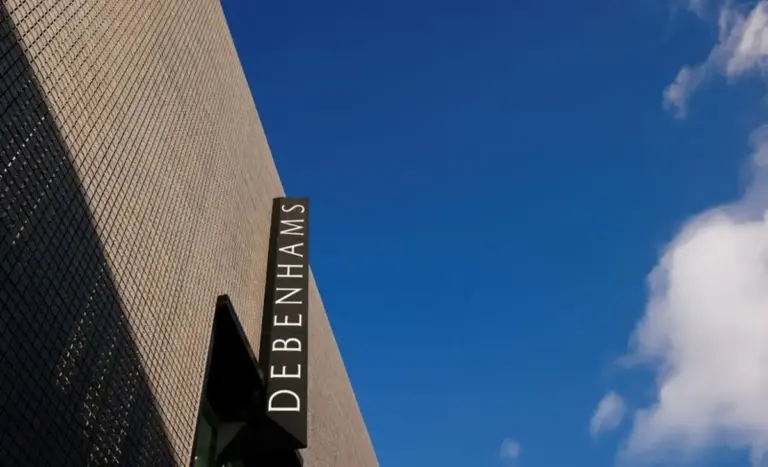 Exterior view of a Debenhams store sign against a blue sky