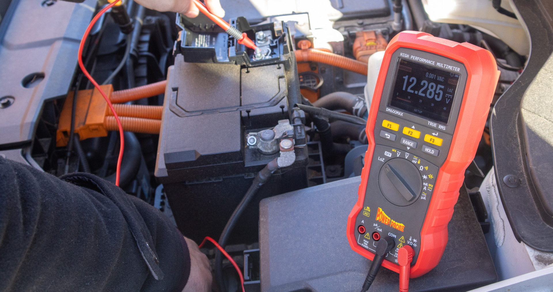 Technician using a Power Probe diagnostic multimeter to test a vehicle's electrical system under the hood