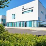 Exterior of Spire Shawfair Park Hospital, a modern white building with glass frontage and the Spire logo on the facade