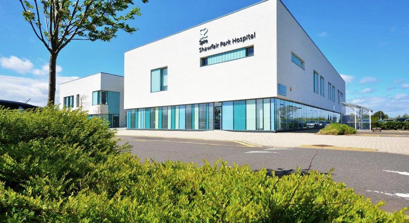Exterior of Spire Shawfair Park Hospital, a modern white building with glass frontage and the Spire logo on the facade