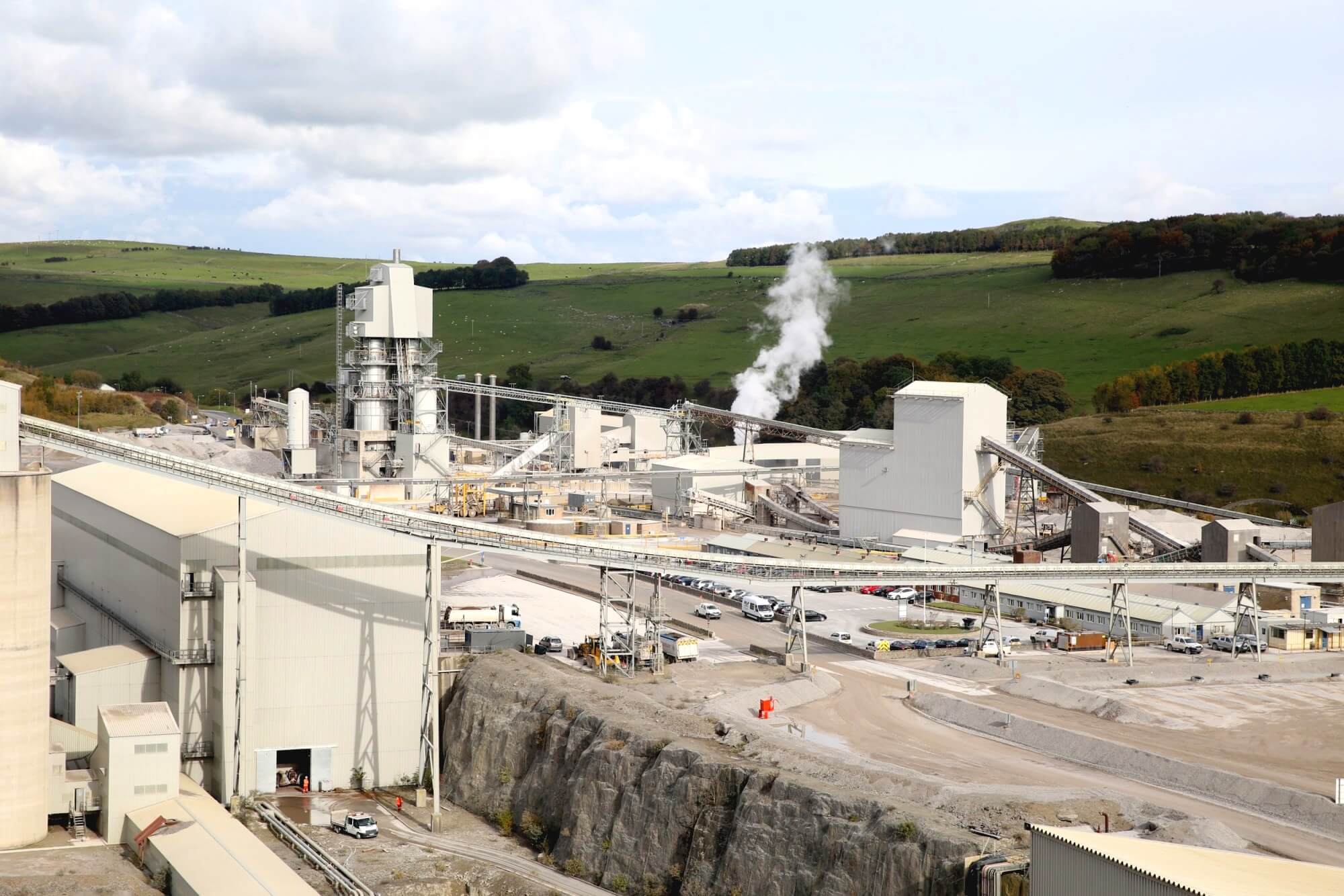 Aerial view of a lime processing plant and quarry set within green countryside hills