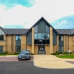 Exterior of a modern care home building with landscaped grounds and parking area, representing Target Healthcare REIT's property portfolio.