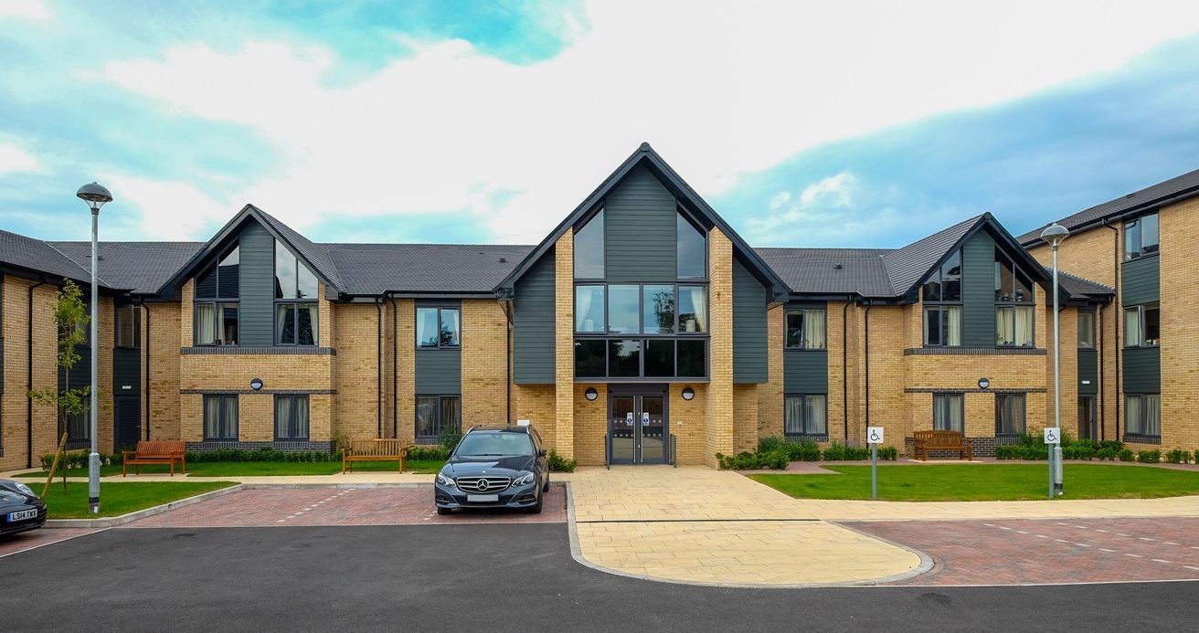 Exterior of a modern care home building with landscaped grounds and parking area, representing Target Healthcare REIT's property portfolio.