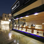 Exterior night view of a Winkworth estate agency branch with illuminated sign and window displaying property listings.