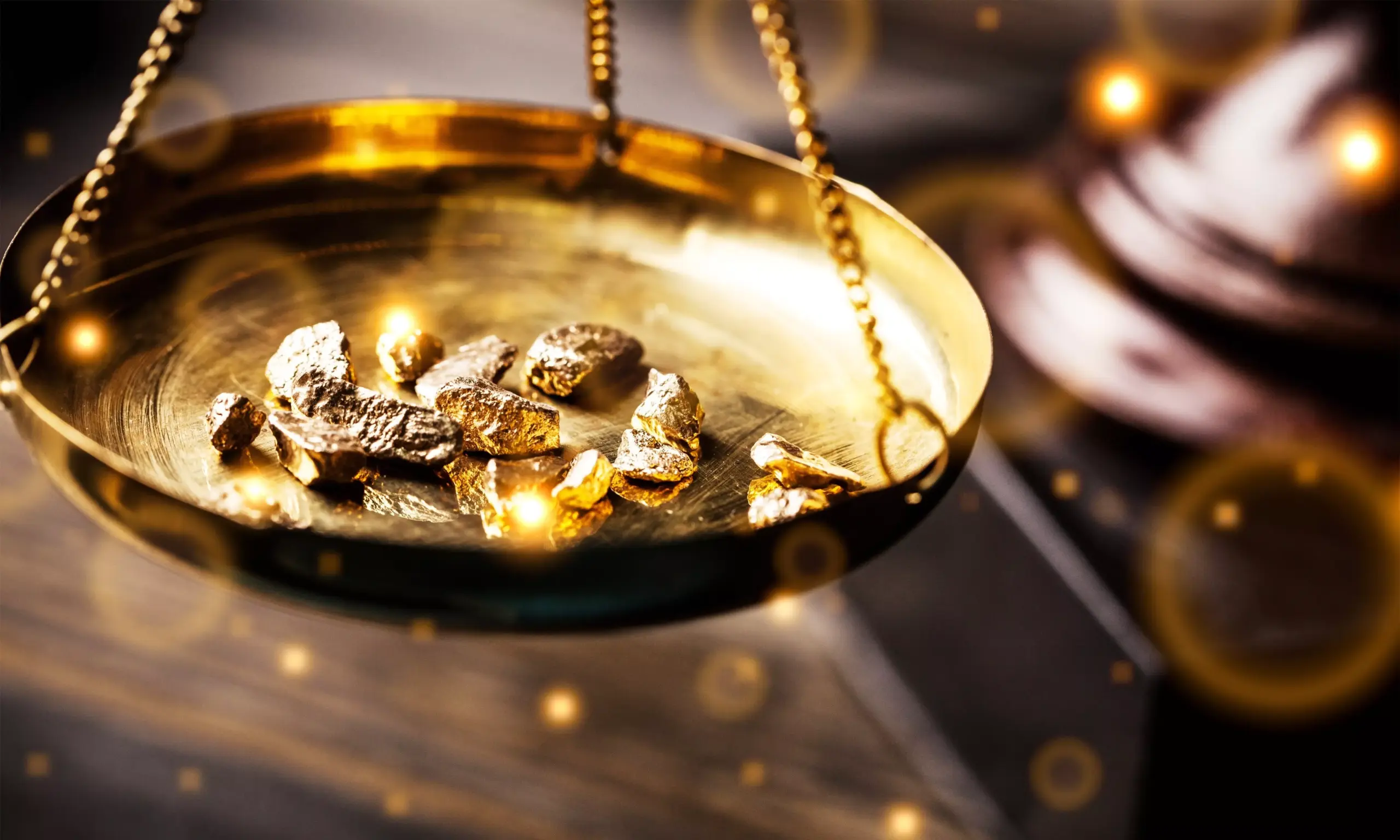 Raw gold nuggets piled on a brass weighing scale, symbolising precious metal value and commodity prices
