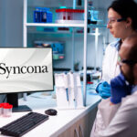 Scientists in a laboratory with a computer monitor displaying the Syncona logo, representing Syncona's life-sciences investment focus