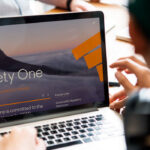 Person using a laptop showing the Ninety One website homepage with the tagline "investing for a world of change"