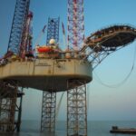 Offshore jack-up oil drilling rig 'Ocean Sovereign' at sea with a support vessel nearby, representing oil and gas exploration operations.