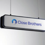 Close Brothers logo sign hanging from cables against a grey background