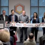IonQ executives and partners cutting a ceremonial ribbon at the opening of a quantum computing manufacturing facility, with IonQ branding visible in the background.