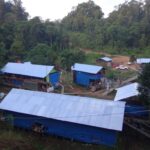 Aerial view of a jungle exploration camp with blue-roofed buildings, representing Asiamet Resources' Indonesian project site.