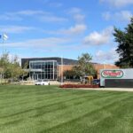 Hormel Foods world headquarters building with company sign and flags behind a mown lawn under a blue sky