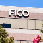 FICO sign on the facade of a corporate office building under a blue sky, with trees in the foreground