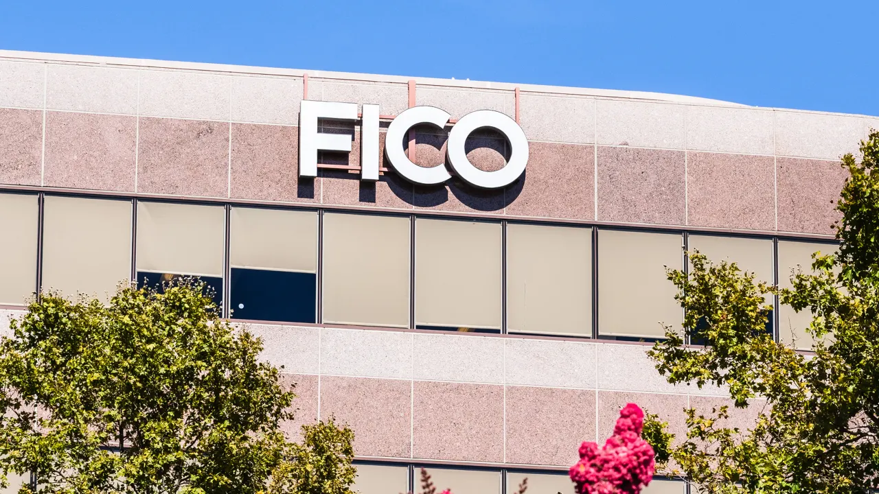 FICO sign on the facade of a corporate office building under a blue sky, with trees in the foreground