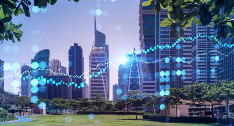 Modern city skyline of glass office towers seen across a park, overlaid with a rising blue financial chart line