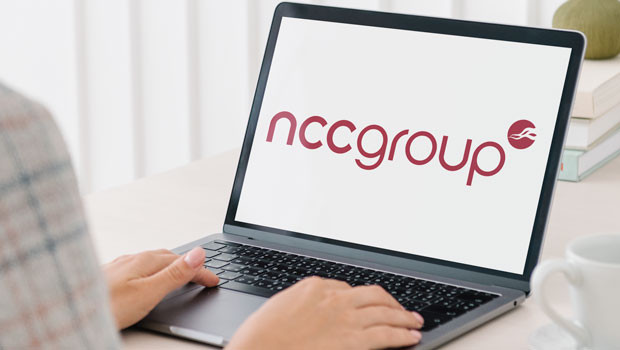 Person typing on a laptop whose screen shows the NCC Group logo