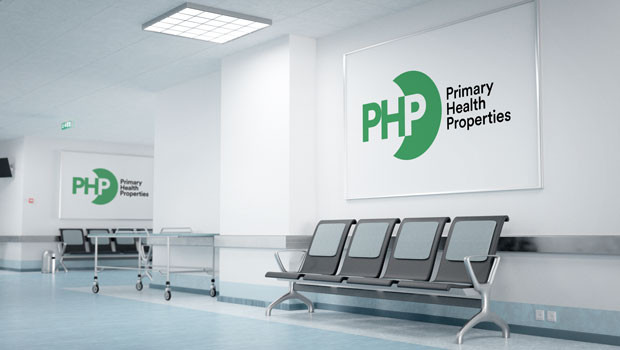 Hospital corridor with waiting chairs and wall signs showing the Primary Health Properties (PHP) logo