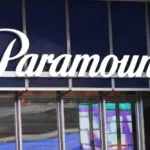 White Paramount script sign on a navy glass building facade above reflective windows