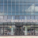 Entrance of a glass office building with 'Utility Warehouse' lettering above a revolving door