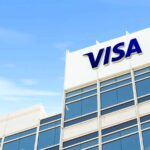 Visa logo on the rooftop of a white and glass office building against a blue sky