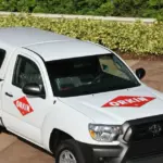White Orkin service truck with red diamond logos parked beside landscaped shrubs